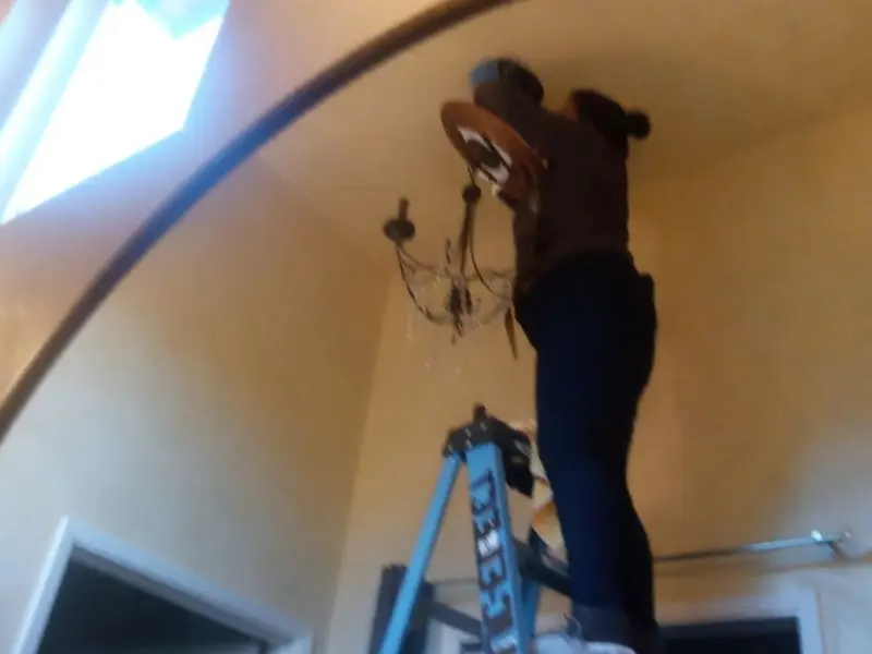 Electrician installing a chandelier in a Hollywood Park residence